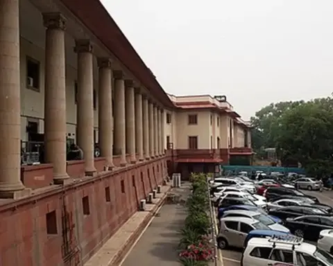 Frontal exterior view of the red sandstone and white central dome of the Supreme Court of India building in New Delhi.