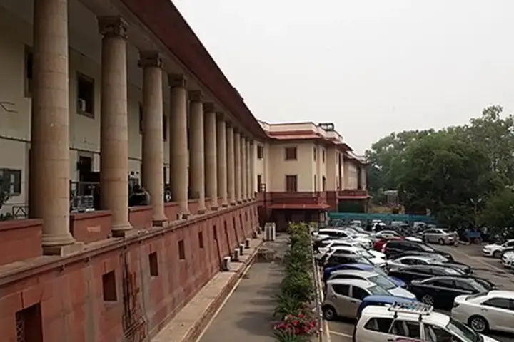 Frontal exterior view of the red sandstone and white central dome of the Supreme Court of India building in New Delhi.