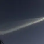 SpaceX Falcon 9 second-stage rocket exhaust plume glowing against the twilight sky, forming an expanded jellyfish-shaped cloud.