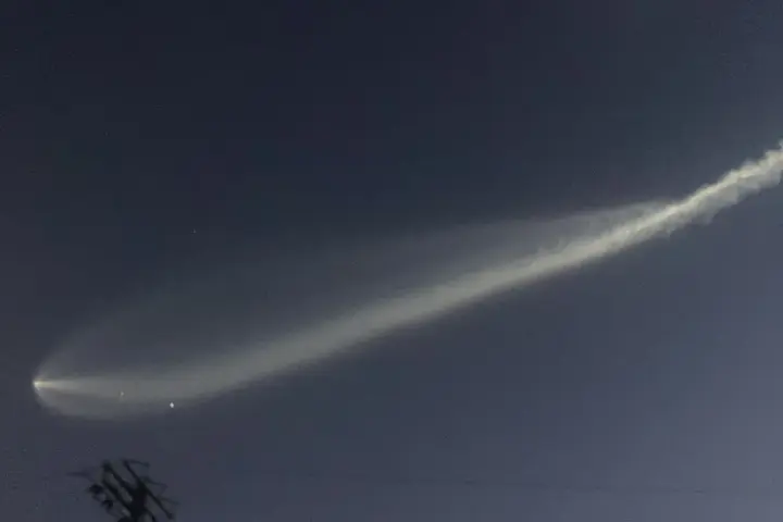 SpaceX Falcon 9 second-stage rocket exhaust plume glowing against the twilight sky, forming an expanded jellyfish-shaped cloud.