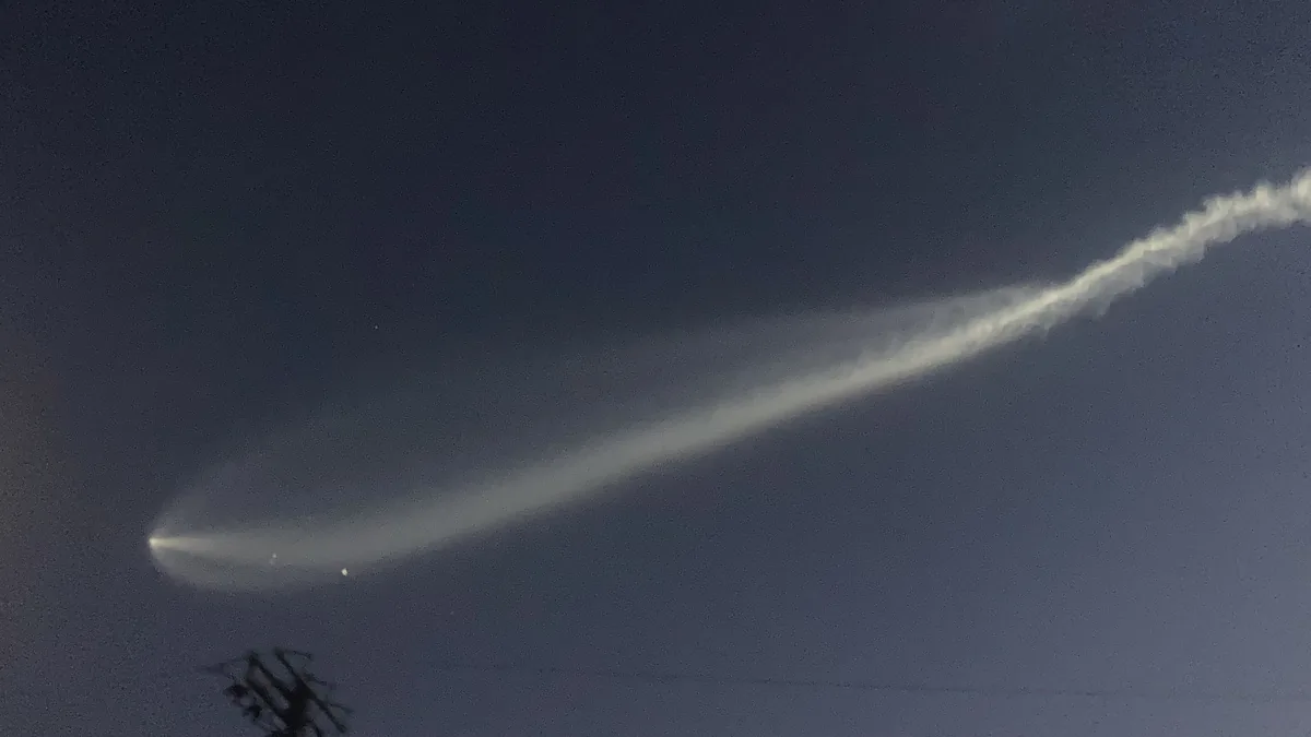 SpaceX Falcon 9 second-stage rocket exhaust plume glowing against the twilight sky, forming an expanded jellyfish-shaped cloud.