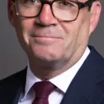 Official portrait photograph of British Prime Minister Andy Burnham in formal parliamentary attire.