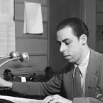 A radio announcer works beside microphones in a studio.