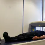 Person undergoing a DEXA body-composition scan in a clinical room, illustrating assessment of body fat distribution.