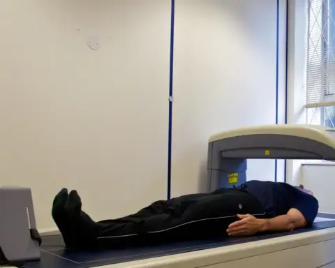 Person undergoing a DEXA body-composition scan in a clinical room, illustrating assessment of body fat distribution.