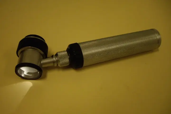A medical practitioner using a dermatoscope to inspect a pigmented mole.