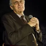 Photograph of actor Alan Alda smiling warmly and speaking during a public question-and-answer event.