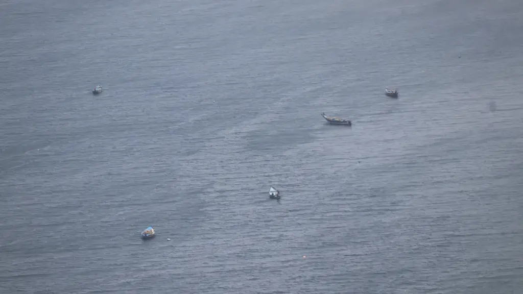 Small wooden fishing boats scattered across the water of the Bay of Bengal near Visakhapatnam