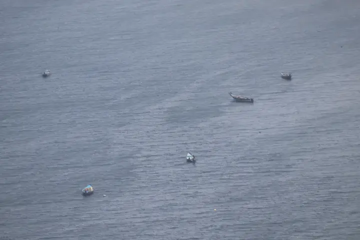 Small wooden fishing boats scattered across the water of the Bay of Bengal near Visakhapatnam