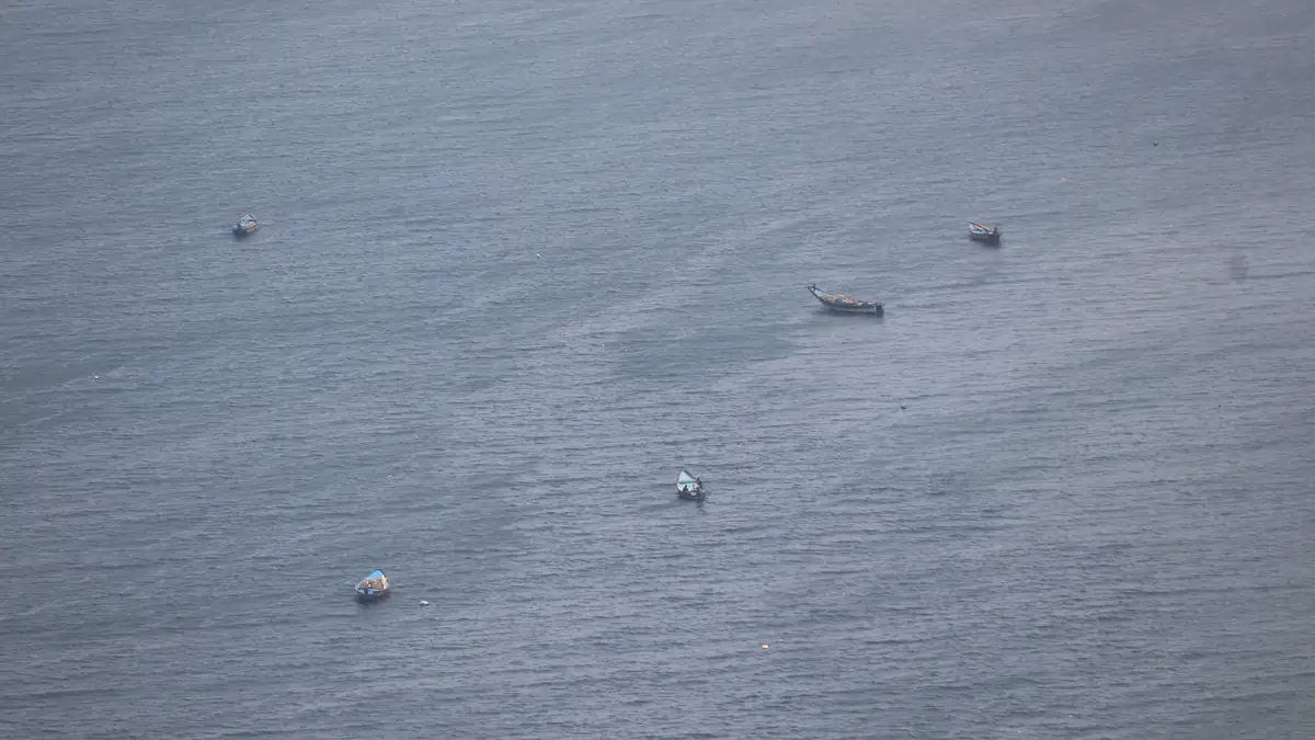 Small wooden fishing boats scattered across the water of the Bay of Bengal near Visakhapatnam