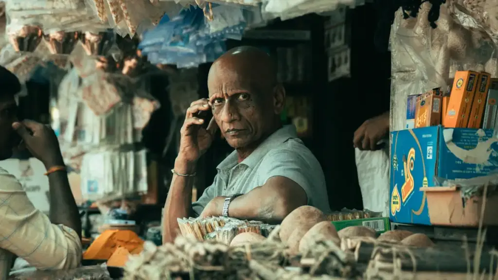 A shopkeeper at a market stall in India, representing the informal and self-employed workforce