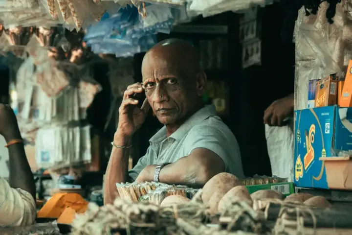 A shopkeeper at a market stall in India, representing the informal and self-employed workforce