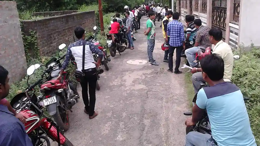 Riders and motorcycles lined up for a two-wheeler driving test at an Indian regional transport office ground
