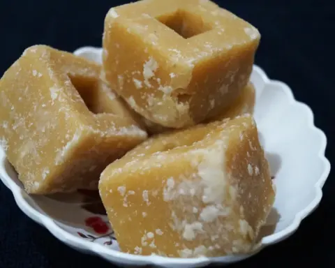 Unrefined golden-brown jaggery gur cubes served on a decorative plate