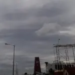 Dark cyclonic storm clouds over RK Beach Road in Visakhapatnam, Andhra Pradesh, showing stripped metal billboard frames and coastal structures battered by severe Bay of Bengal winds.