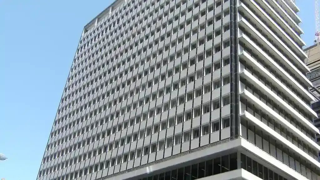 Exterior view of the Reserve Bank of Australia headquarters building at 65 Martin Place in Sydney, New South Wales, under a bright blue sky.