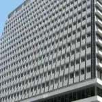 Exterior view of the Reserve Bank of Australia headquarters building at 65 Martin Place in Sydney, New South Wales, under a bright blue sky.