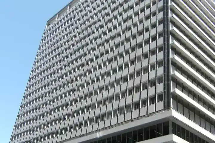 Exterior view of the Reserve Bank of Australia headquarters building at 65 Martin Place in Sydney, New South Wales, under a bright blue sky.