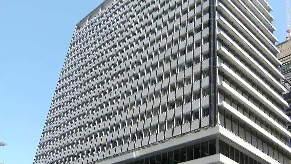 Exterior view of the Reserve Bank of Australia headquarters building at 65 Martin Place in Sydney, New South Wales, under a bright blue sky.