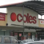 Exterior view of a Coles supermarket entrance at Kurralta Central in Australia with a curved roof awning and parked vehicles in the car park.