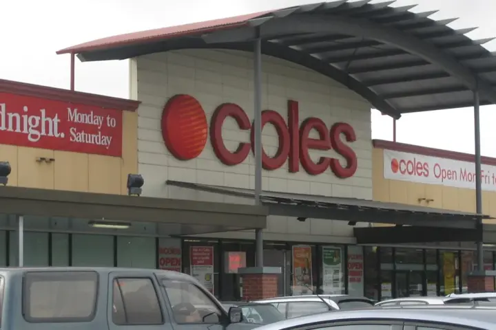 Exterior view of a Coles supermarket entrance at Kurralta Central in Australia with a curved roof awning and parked vehicles in the car park.