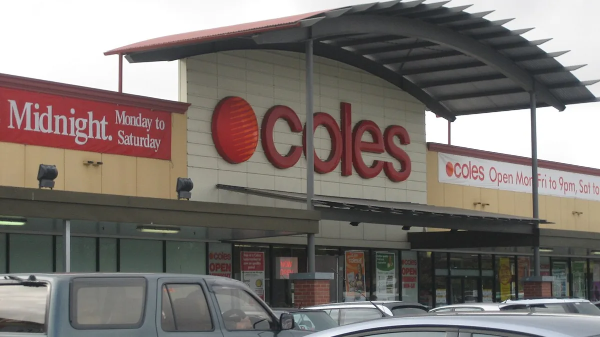 Exterior view of a Coles supermarket entrance at Kurralta Central in Australia with a curved roof awning and parked vehicles in the car park.