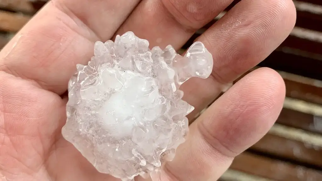 Close-up photograph of a person holding a large, spiky, translucent and white hailstone over a wooden deck in South-East Queensland.