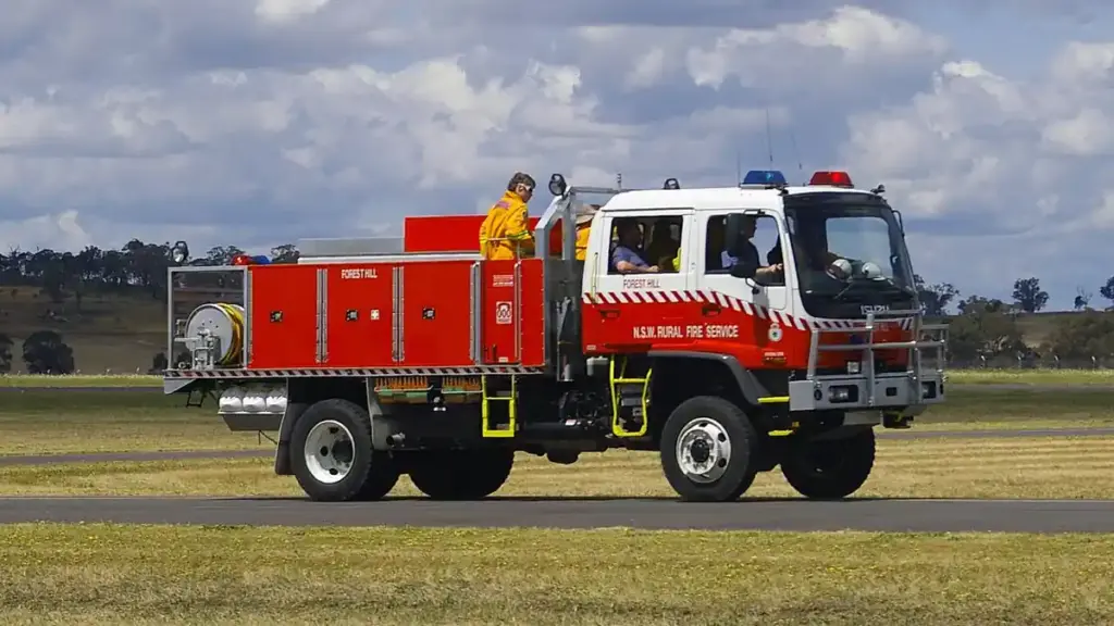 A white and red New South Wales Rural Fire Service heavy 4WD bushfire tanker parked on tarmac during emergency preparedness operations.