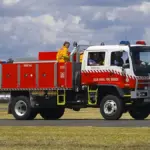 A white and red New South Wales Rural Fire Service heavy 4WD bushfire tanker parked on tarmac during emergency preparedness operations.