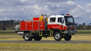 A white and red New South Wales Rural Fire Service heavy 4WD bushfire tanker parked on tarmac during emergency preparedness operations.