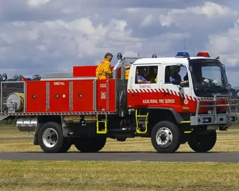 A white and red New South Wales Rural Fire Service heavy 4WD bushfire tanker parked on tarmac during emergency preparedness operations.