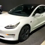 White Tesla Model 3 electric sedan photographed indoors.