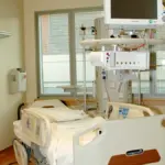 Empty hospital patient room with a single bed.