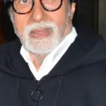 Indian actor Amitabh Bachchan photographed in close-up wearing a dark hooded jacket