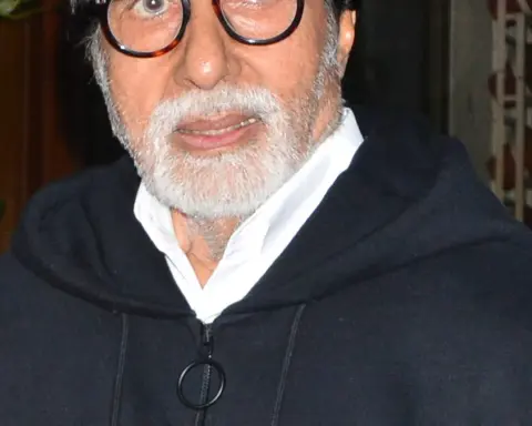 Indian actor Amitabh Bachchan photographed in close-up wearing a dark hooded jacket