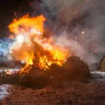 A bonfire burning on a beach at night.
