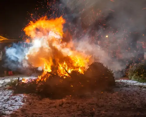 A bonfire burning on a beach at night.