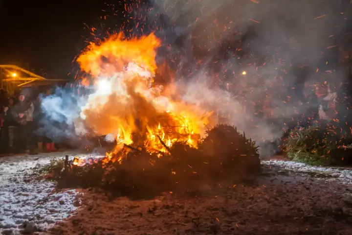 A bonfire burning on a beach at night.