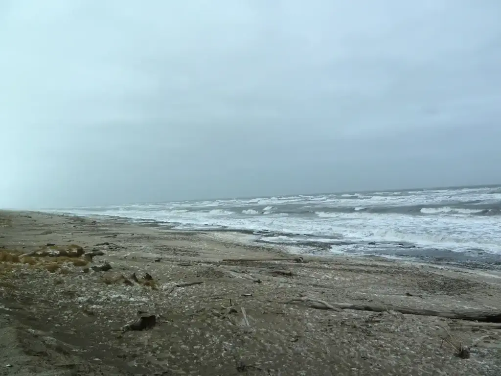 Churning grey seas and surf along a coastal beach during a storm.