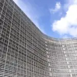 Wide-angle photograph of the glass-and-steel facade of the European Commission Berlaymont building under daylight in Brussels.