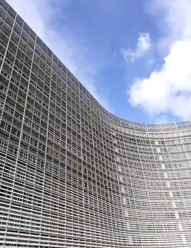 Wide-angle photograph of the glass-and-steel facade of the European Commission Berlaymont building under daylight in Brussels.