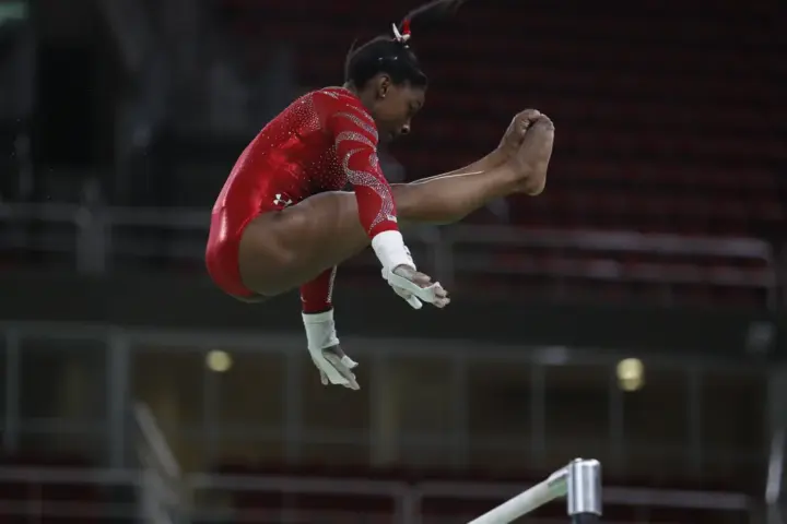 Simone Biles performing a release move on the uneven bars during training at the Rio 2016 Olympics