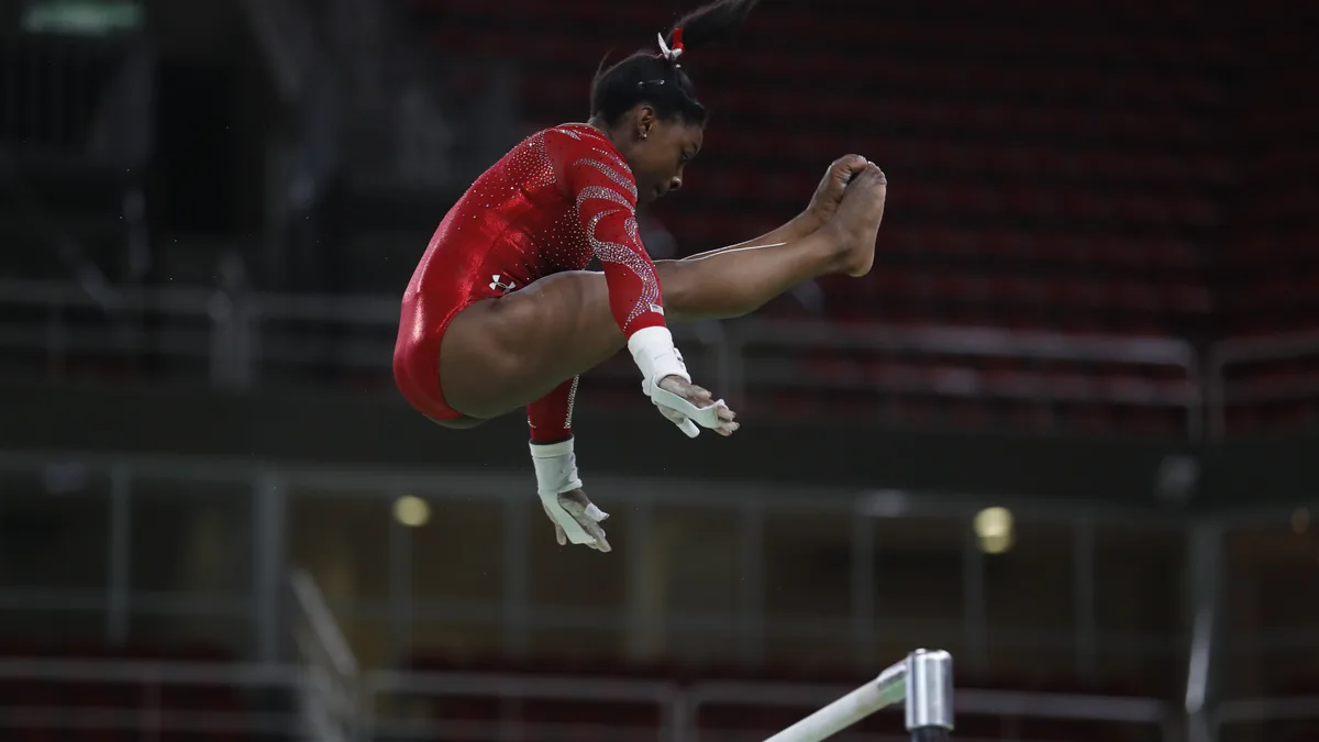 Simone Biles performing a release move on the uneven bars during training at the Rio 2016 Olympics
