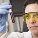 Medical laboratory technician preparing vacutainer blood collection tubes for metabolic centrifugation.