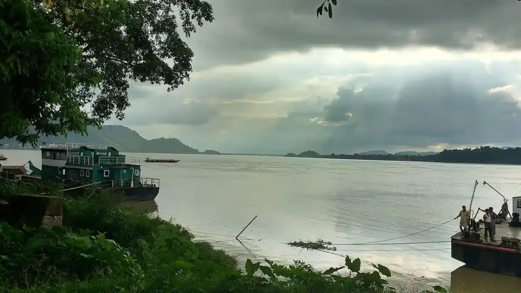 Wide waters of the Brahmaputra River with hilly riverbanks in Guwahati, Assam.