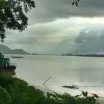 Wide waters of the Brahmaputra River with hilly riverbanks in Guwahati, Assam.