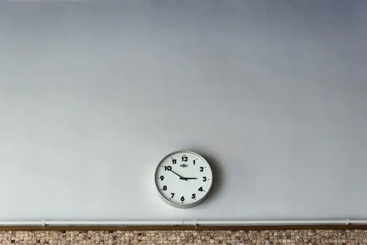Close-up of a round analog wall clock face with clean hour numerals and dark hands.