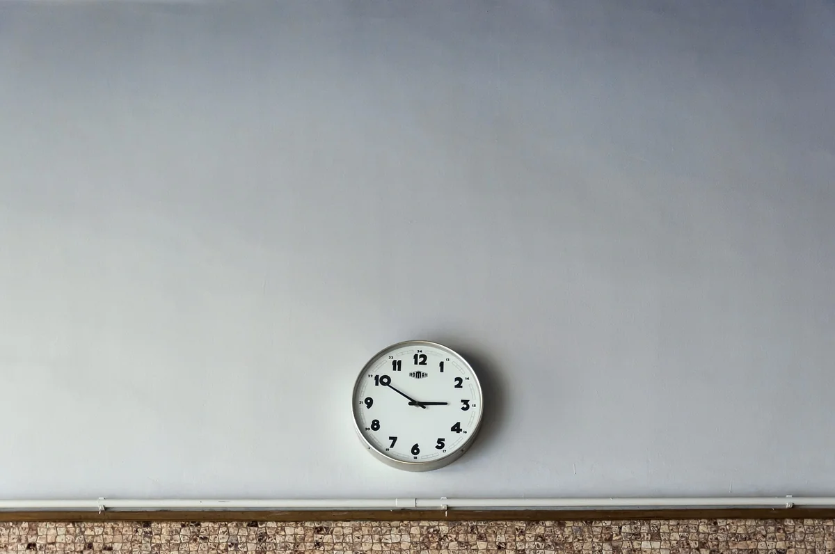 Close-up of a round analog wall clock face with clean hour numerals and dark hands.