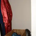 A wardrobe with hanging garments and a basket of folded clothing.