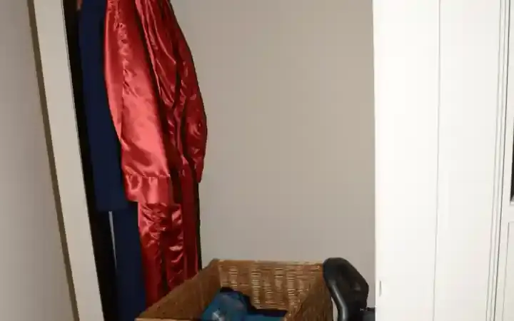 A wardrobe with hanging garments and a basket of folded clothing.